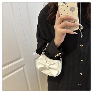 Close-up of white shoulder bag featuring a large bow and elegant pearl beaded handle