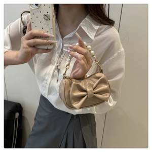 Detail view of khaki mini bag featuring bow design and luxury faux pearl top handle