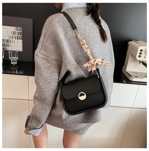 Black shoulder bag featuring a gold ring clasp and polka dot scarf wrapped strap