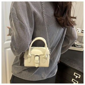 Chic mini hand-carried crossbody bag in creamy white with silver chain strap shown on model