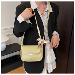 Detail of buttery yellow PU leather shoulder bag featuring golden clasp and polka dot scarf