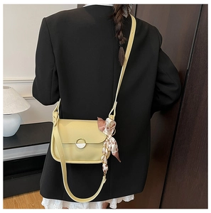 Detail of a lemon yellow crossbody bag with a decorative floral silk scarf and metal clasp