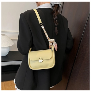 Detail of yellow shoulder bag featuring a silk scarf accent on a black blazer