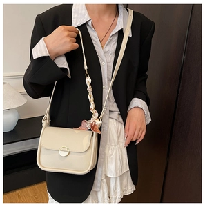 Detail of cream crossbody bag with gold buckle and floral silk scarf on shoulder strap