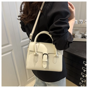 Close-up of cream white crossbody bag with belt buckle detail on neutral background