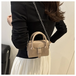 Detail of a mini beige leather crossbody bag featuring a stylish knitted texture buckle strap