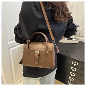 Brown vintage handbag with horseshoe buckle shown on model in a home setting