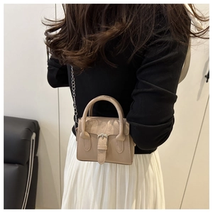Close-up of a mini beige square bag with metal chain strap and retro buckle detail