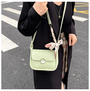 Detail of light green crossbody bag with gold metal buckle and floral silk scarf