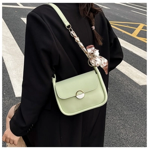 Detail of light green square crossbody bag with silk scarf and gold clasp decoration