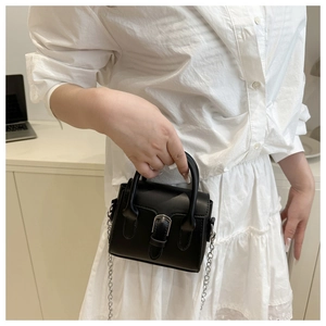 Detail of a black mini square bag with silver buckle and metal chain on a model