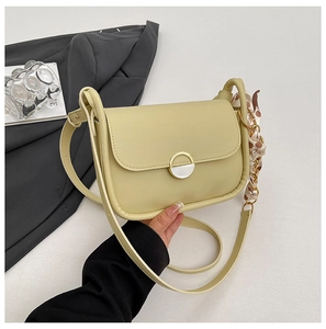 Detail of light yellow crossbody bag with gold enamel clasp and decorative polka dot scarf