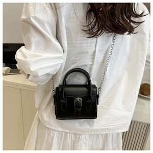 Detailed back view of a mini black leather handbag with silver chain strap on a model