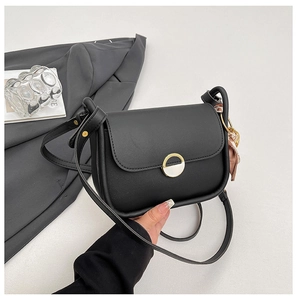 Detail of black crossbody bag featuring a round metal clasp and pink floral silk scarf decoration