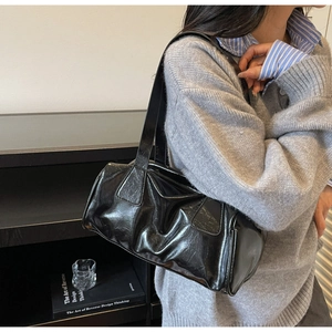 Glossy black baguette bag with retro pleated leather texture worn under the arm