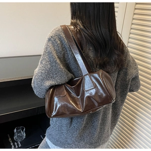 Detail of vintage dark brown glossy pillow bag with wrinkled faux leather texture