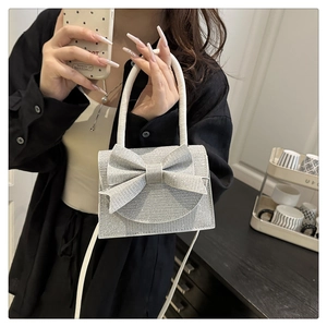 Detail of silver glitter mini bag with large bow decoration and white tubular handle