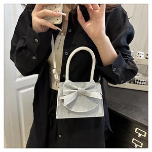 Silver glitter evening bag featuring a large bow detail and sleek metal chain strap
