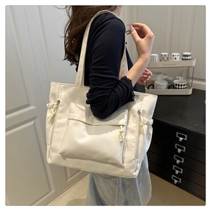Detail of white nylon tote bag with front flap pocket and side drawstring details
