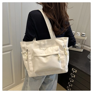 Detail of off-white large tote bag showing front pocket and side drawstring accents