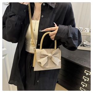 Close-up of champagne gold glitter evening bag with large bow and top handle