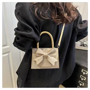 Detail of elegant gold evening bag featuring a large bow and sparkling sequined texture