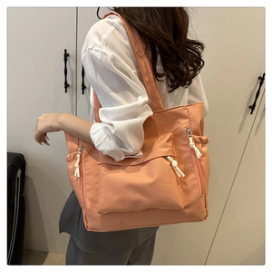 Detail of coral pink tote bag showing the water-resistant nylon texture and side pockets