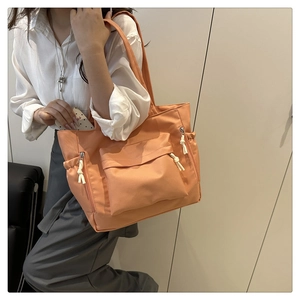 Detail of coral orange tote bag showing functional large front pockets and drawstring design
