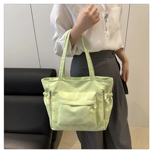 Detailed view of spacious light green nylon tote bag featuring functional outer pockets