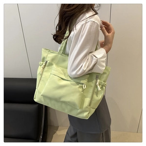 Detailed back view of a light green nylon dumpling bag with multi-pocket design on model