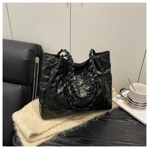 Close-up of black tote bag with quilted bear pattern and chunky chain shoulder strap