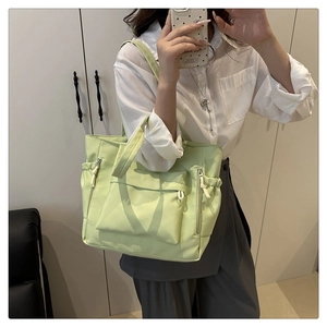 Detail of light green tote bag with large front zipper pocket and side drawstring