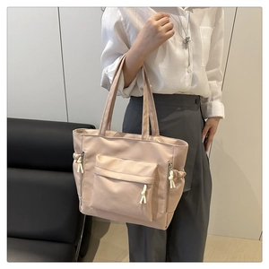 Close-up of beige tote bag with functional front flap pocket and side drawstring pockets
