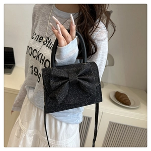 Détail du mini sac carré à paillettes noires avec grand nœud et poignée ronde