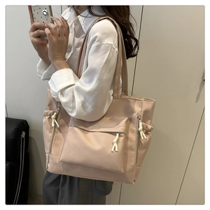 Detail of light pink large capacity tote bag featuring front zip pocket and side compartments