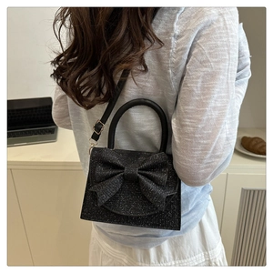 Détail du sac de soirée chic noir scintillant avec grand nœud et poignée ronde