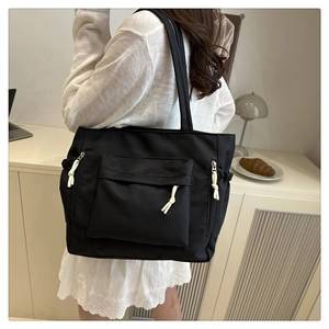Detail view of black oxford tote bag featuring multi-pocket design and white rope pulls