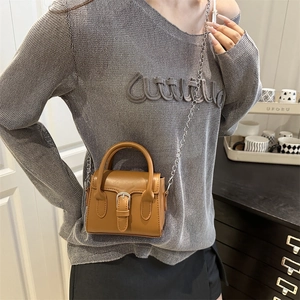 Mini brown leather crossbody bag with metal buckle and chain strap on female model