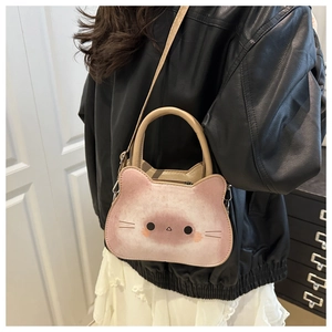 Pink cat-shaped crossbody bag shown on model with adjustable strap and handle