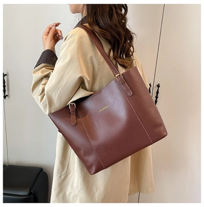 Sac cabas en cuir PU marron rouge porté par un mannequin en trench-coat élégant