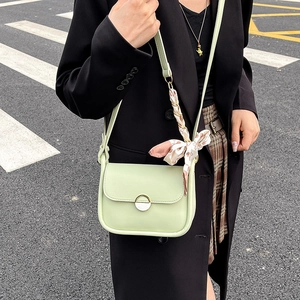Mint green leather crossbody bag with metal ring buckle and floral scarf on a model