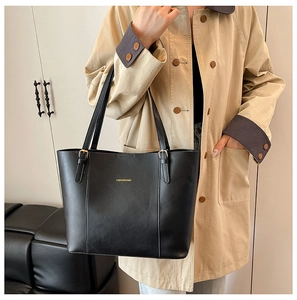 Détail de la bandoulière réglable et logo doré sur le cabas en cuir grainé noir