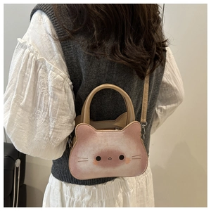 Close-up of pink cat-shaped PU leather crossbody bag with cartoon face and shoulder strap