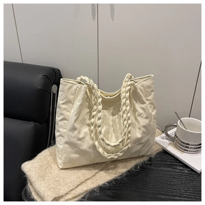 Detail view of cream tote bag featuring embossed bear pattern and woven handles