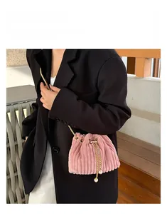 Pink corduroy drawstring bucket bag with gold chain strap and pearl charms on a model