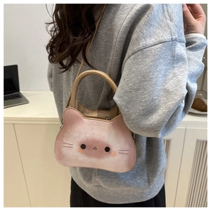 Pink cartoon cat crossbody bag made of PU leather shown on shoulder for size reference