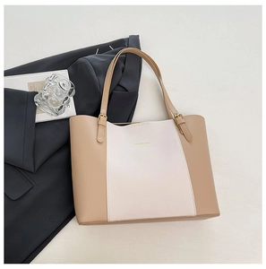Détail du sac cabas bicolore avec logo et boucles métalliques dorées sur similicuir de luxe