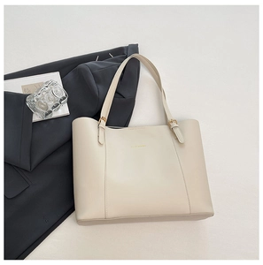 Détail du cabas élégant en cuir PU beige avec logo doré et accents de boucles métalliques