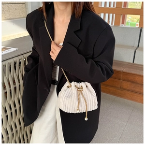 Close-up of drawstring corduroy bucket bag with gold chain and pearl accents