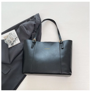 Détail d'un grand sac cabas en cuir PU noir avec lettrage doré et boucles métalliques